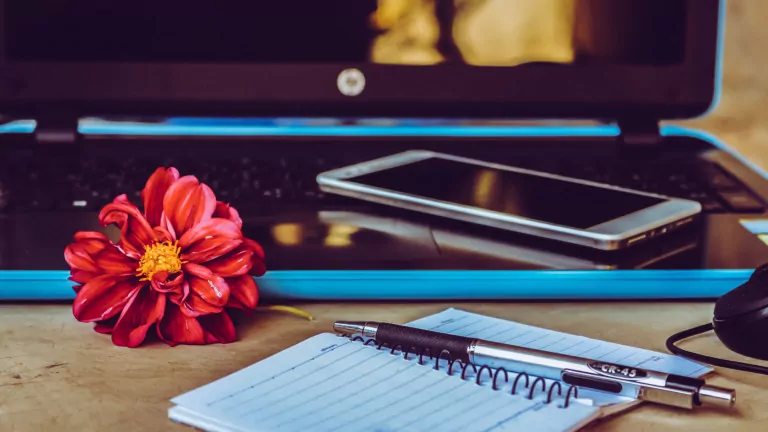 Canva - White Smartphone on Black Laptop Next to Pen on White Notepad